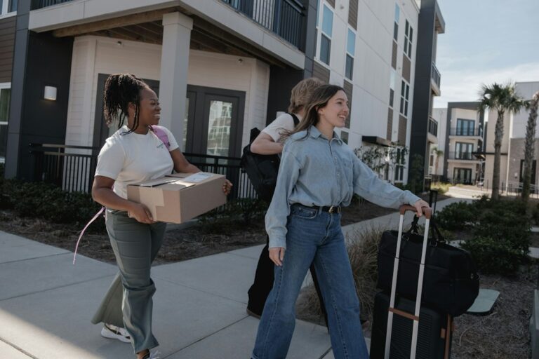 Jeunes locataires avec cartons et valise devant un immeuble