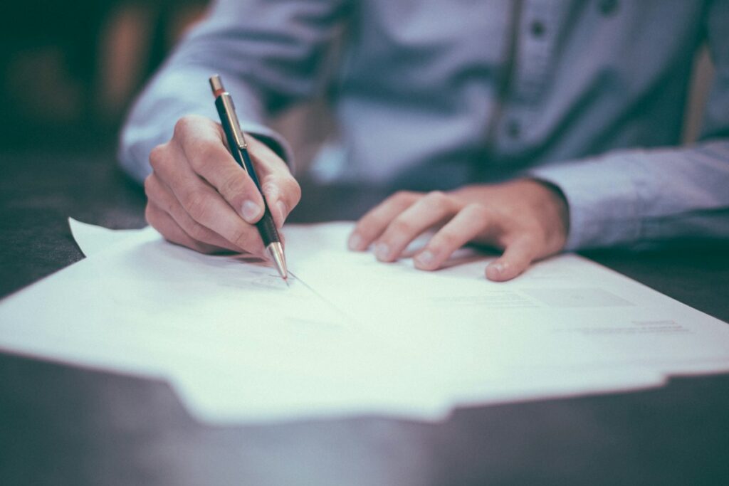 Main signant un document au stylo