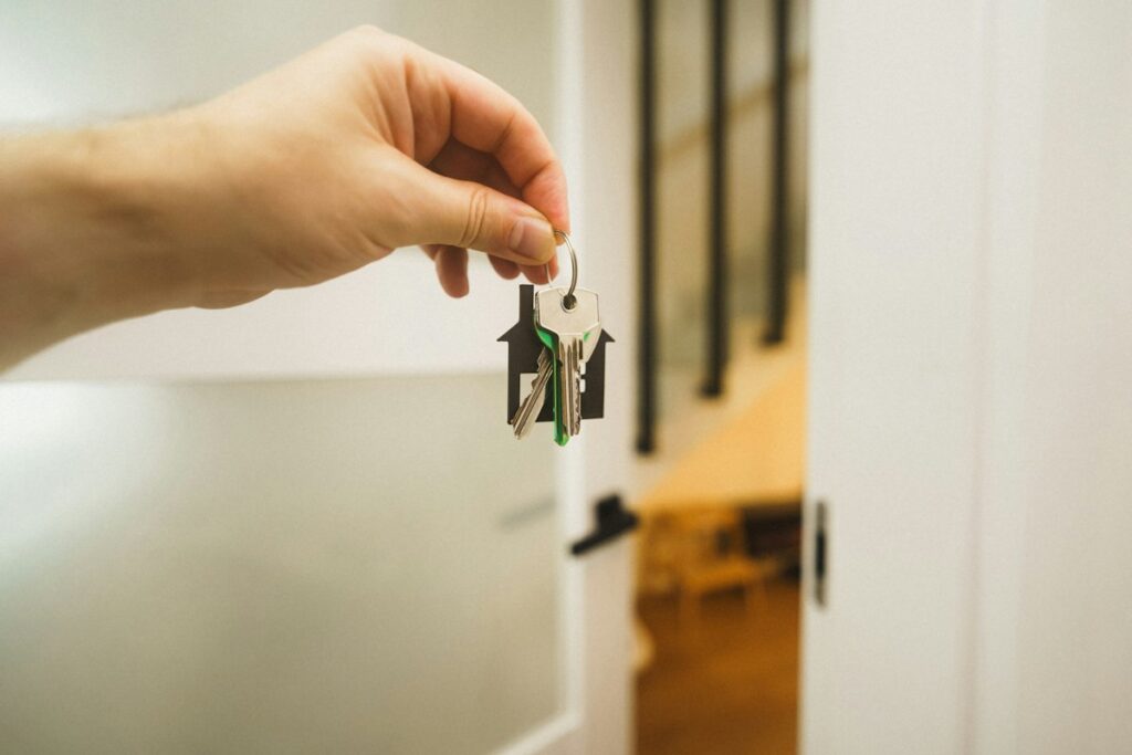 Main tenant les clés devant une porte d’entrée