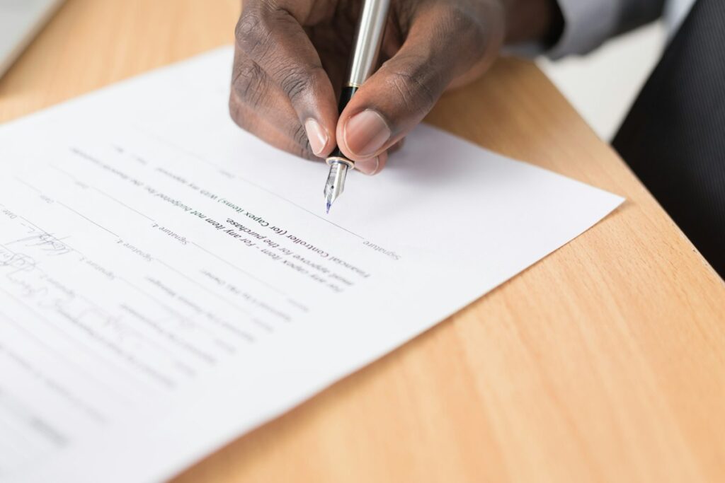 Main signant un document au stylo-plume